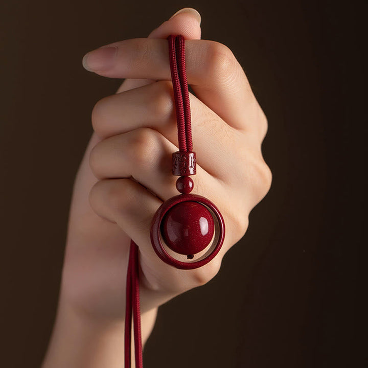 Rote Zinnober PiXiu Kette mit Glücksstein in Hand gehalten elegant.