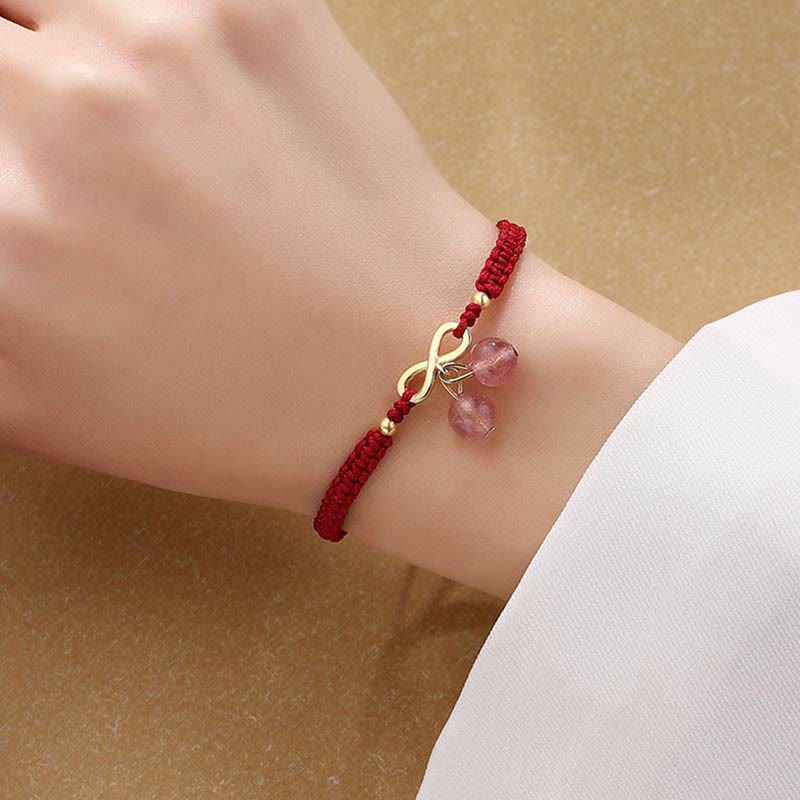 Rotes Armband mit Erdbeerquarz Kristall und goldener Schleife am Handgelenk.