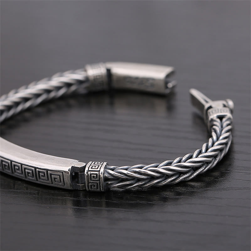 Silbernes Armband mit Muster und geflochtener Textur auf schwarzem Untergrund.