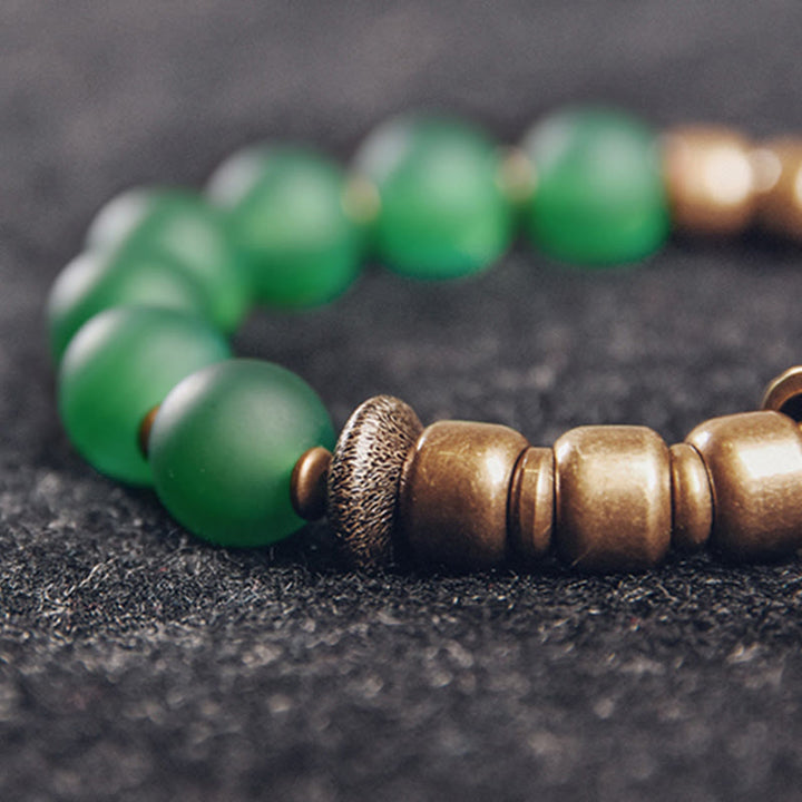 Grünes Jade Armband mit bronzefarbenen Perlen auf dunklem Hintergrund elegant.