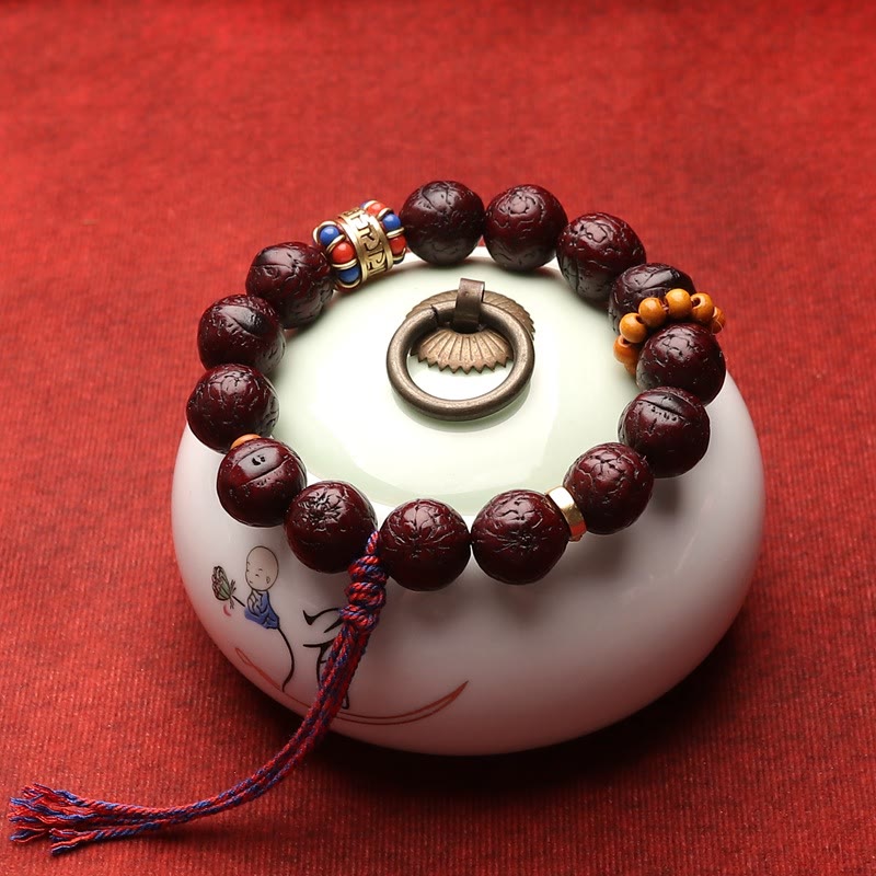 Bodhi Armband mit dunkelroten Perlen und Metallverzierungen auf Weiß.