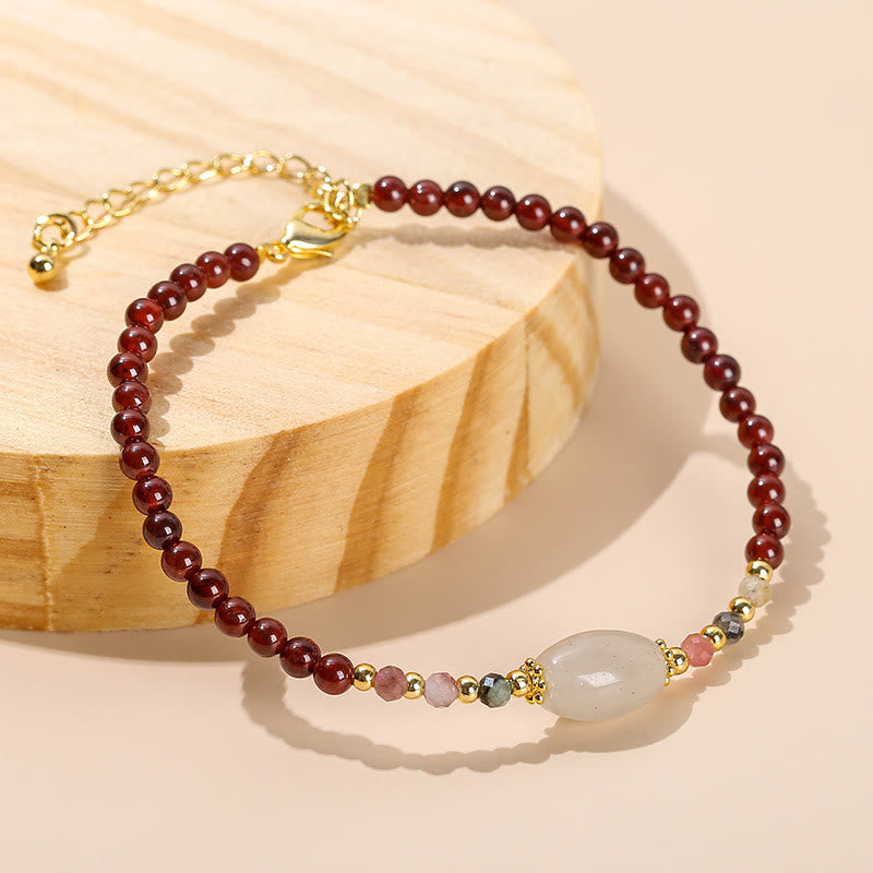 Armband Granat Jade mit weißem Stein elegant auf Holz präsentiert