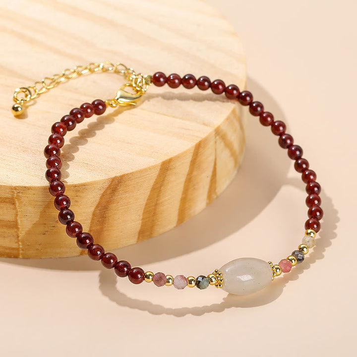 Armband Granat Jade mit weißem Stein elegant auf Holz präsentiert