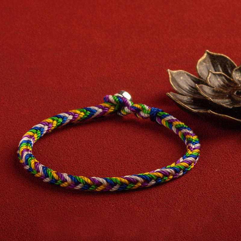 Buntes geflochtenes Armband auf rotem Hintergrund Glück Weg.