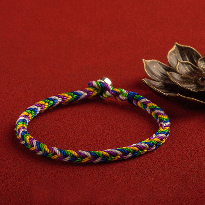 Buntes geflochtenes Armband auf rotem Hintergrund Glück Weg.