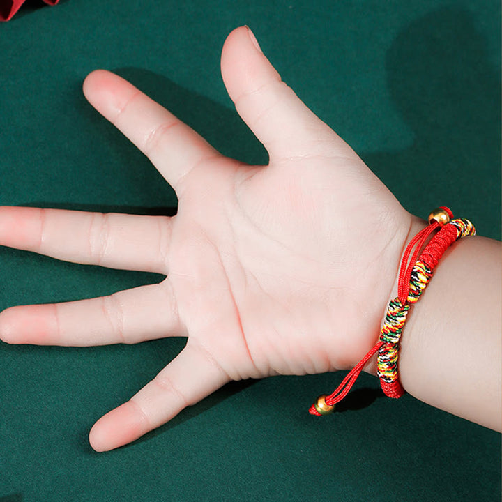 Rotes Armband mit goldenen Perlen am Kinderhandgelenk getragen.