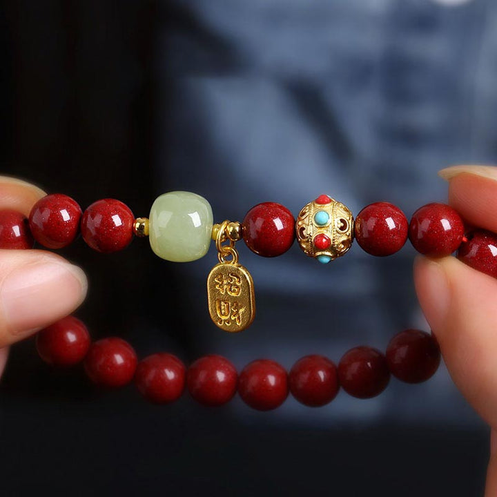Armband Grüner Aventurin Zinnober in Hand gehalten rote Perlen goldene Verzierungen