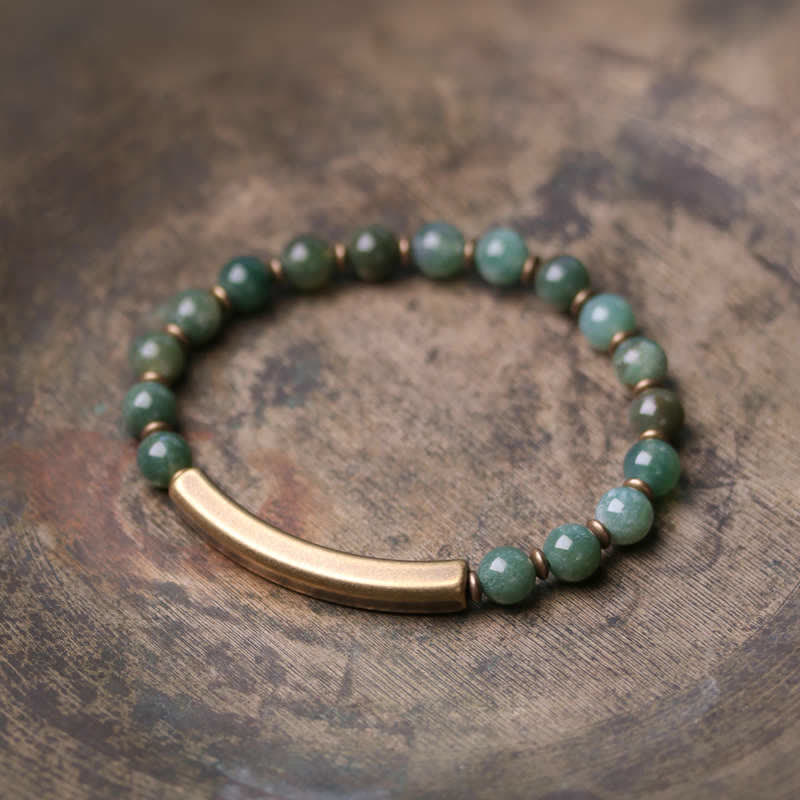 Grünes Stein Armband mit goldenem Rohr auf Holzuntergrund Flat Lay