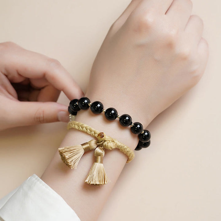 Armband Schwarzer Onyx – Schutz mit goldenen Quasten am Handgelenk getragen