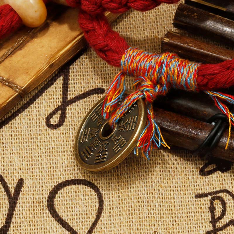 Rotes Armband mit Münze und Holzperlen auf Leinenstoff.