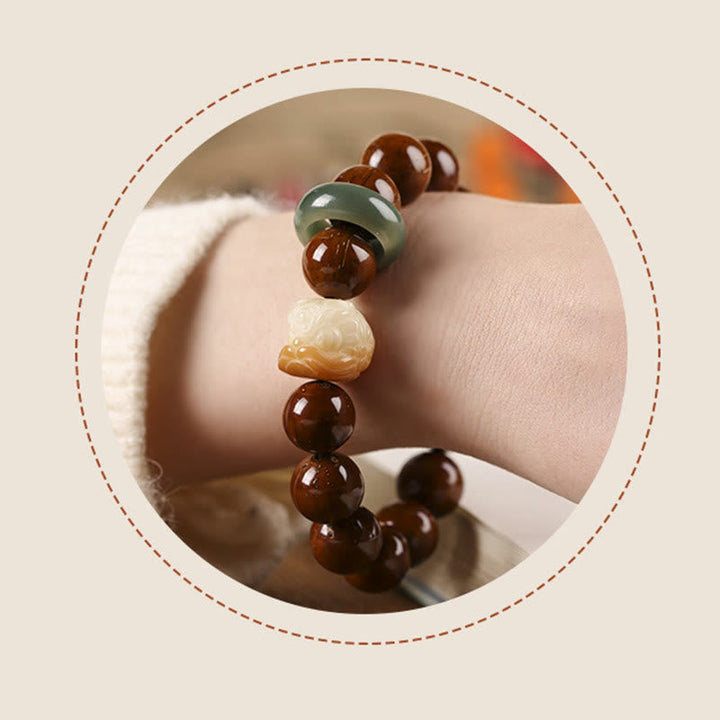 Armband mit braunen Perlen und grünem Stein am Handgelenk getragen.