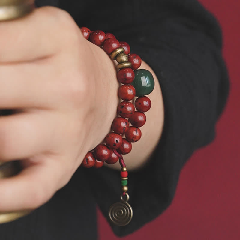 Rotes Perlenarmband mit Jade und Kupfer am Handgelenk getragen.