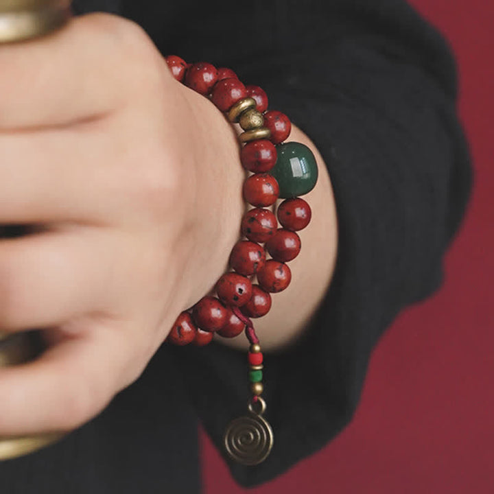 Rotes Perlenarmband mit Jade und Kupfer am Handgelenk getragen.