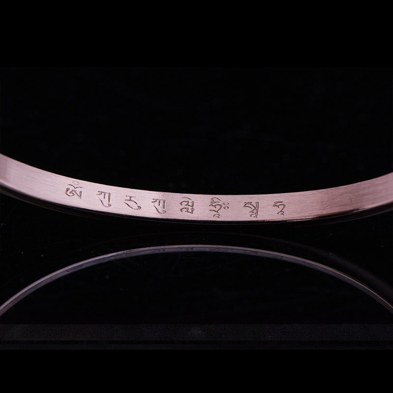 Armband mit graviertem Text am Handgelenk, elegantes Design schwarzer Hintergrund.