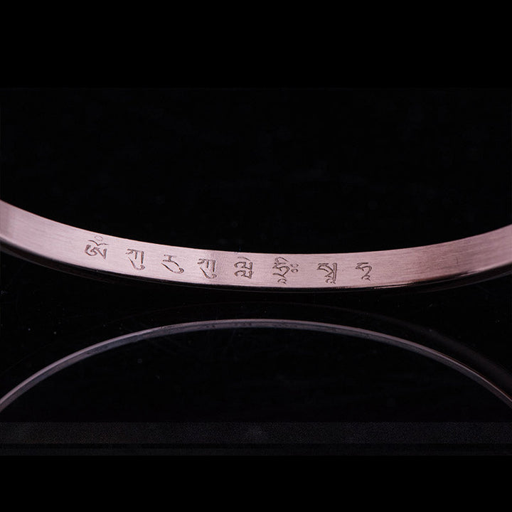 Armband mit graviertem Text am Handgelenk, elegantes Design schwarzer Hintergrund.