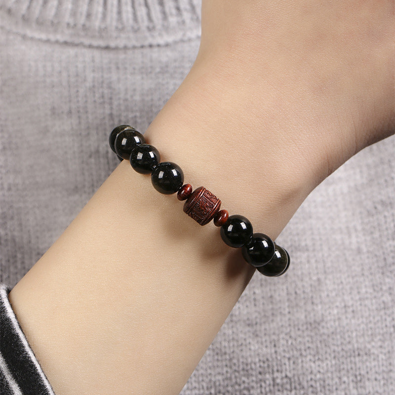 Schwarzes Obsidian Armband mit roten Perlen am Handgelenk getragen