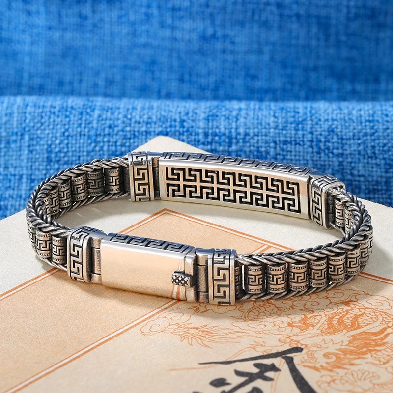 Silbernes Armband mit Grecamuster am Handgelenk elegantes Design getragen