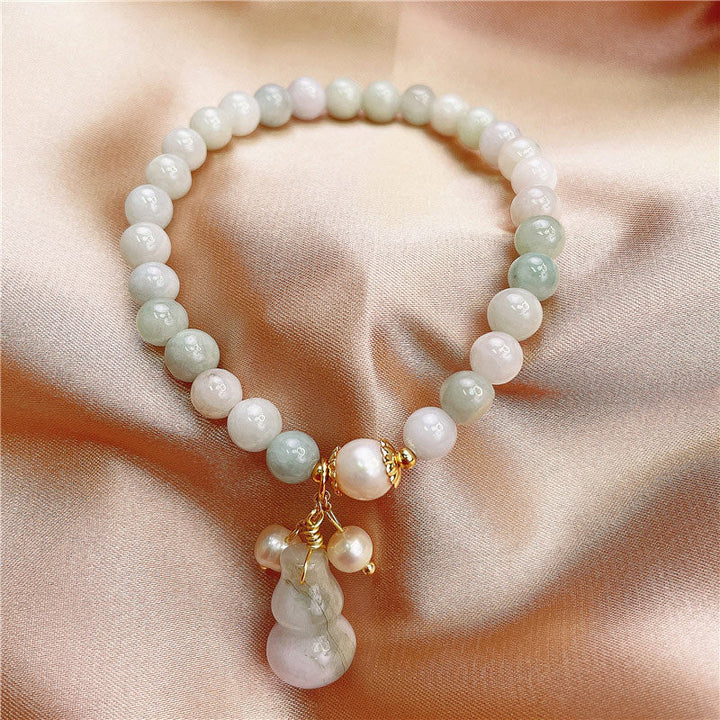 Jade Armband mit weißen und grünen Perlen, goldenem Verschluss und Anhänger.