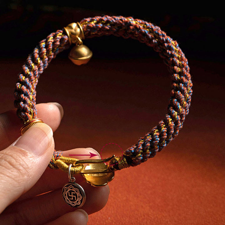 Buntes Armband mit Om-Anhänger am Handgelenk getragen, goldene Verschlüsse.