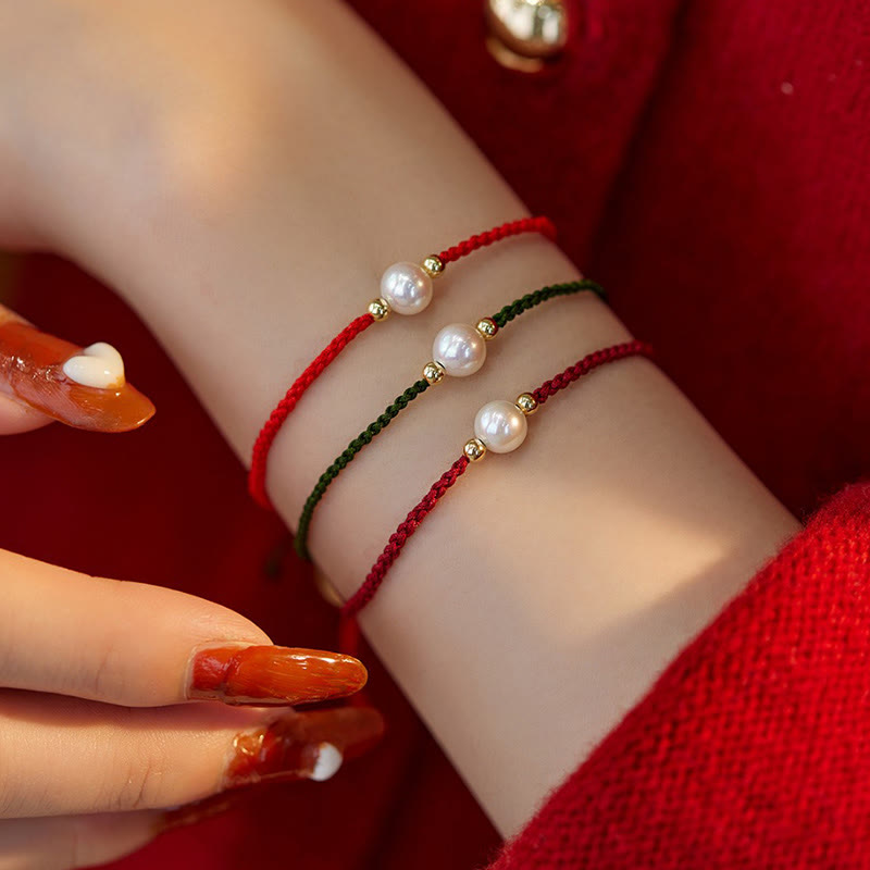 Drei geflochtene Armbänder mit Naturperlen am Handgelenk getragen rot grün