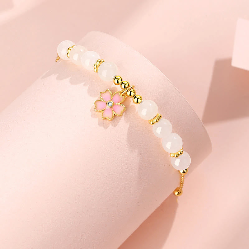 Armband mit weißer Jade und rosa Blütenanhänger elegant getragen