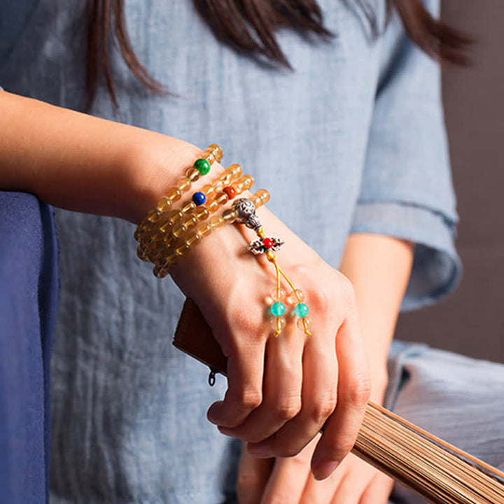 Mala Armband mit goldenen Perlen und bunten Steinen am Handgelenk getragen