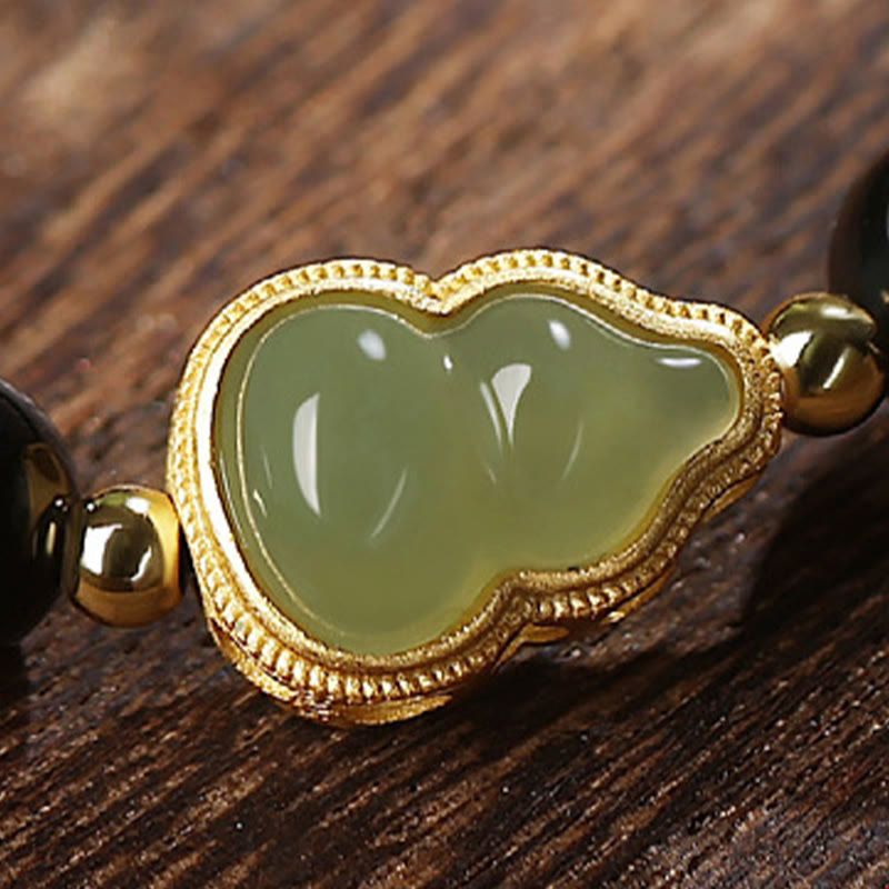 Grünes Jade Buddha Armband mit goldenem Verschluss auf Holzoberfläche.