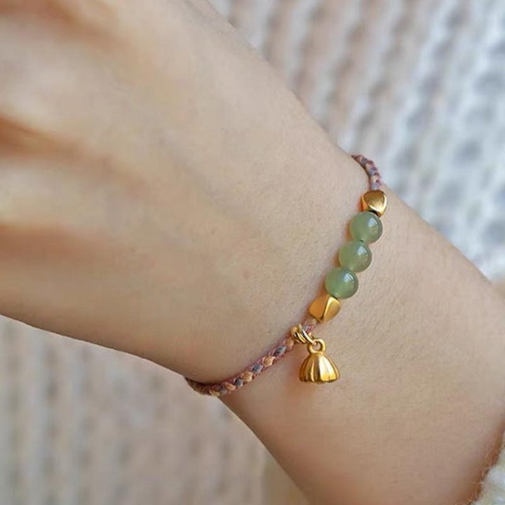 Jade Lotus Armband mit goldenem Anhänger am Handgelenk getragen
