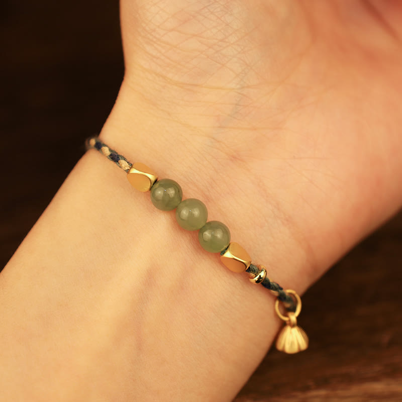 Jade Armband am Handgelenk mit grünen Steinen und Lotus Charm.