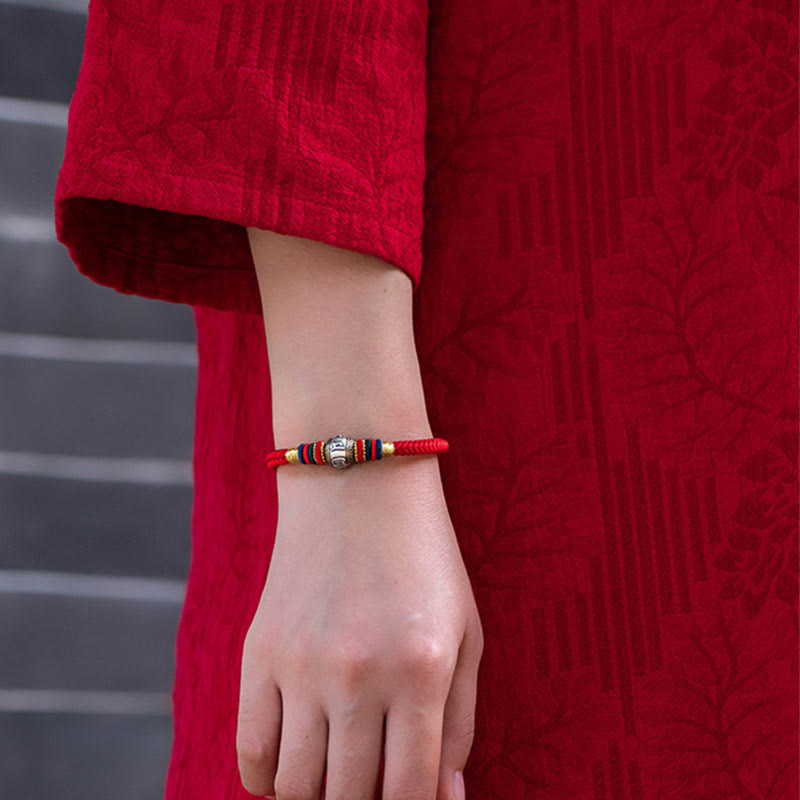 Rotes Armband mit Om Mani Padme Hum Perle elegant am Handgelenk getragen