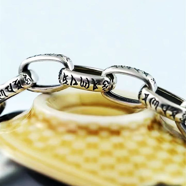 Silber Om Mani Padme Hum Armband auf gelbem Textilhintergrund Nahaufnahme
