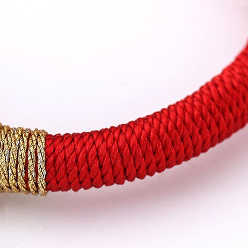 Rotes Armband mit goldenem Verschluss auf hellem Hintergrund elegant.