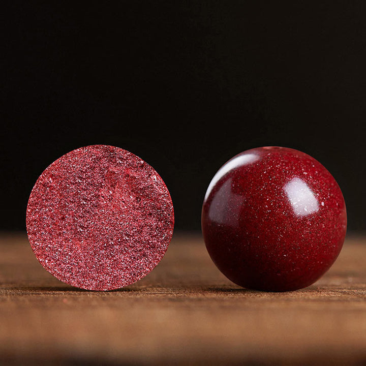Zwei rote Glaskugeln mit Glittereffekt nebeneinander auf Holz.