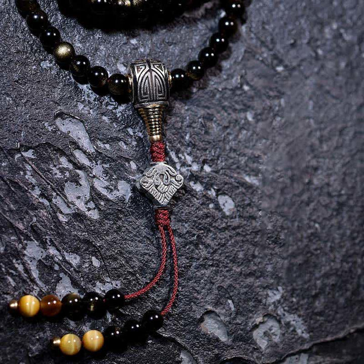 Mala Tigerauge Obsidian Armband mit silbernen Perlen auf Stein.
