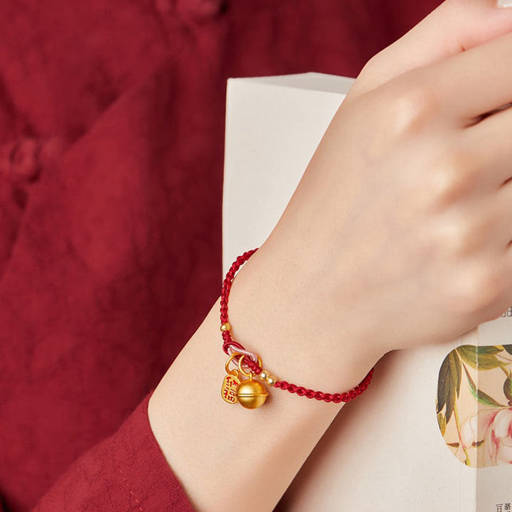 Rotes Armband Fu-Zeichen – Glück mit goldenen Anhängern am Handgelenk.