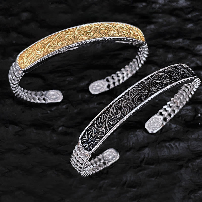 Zwei silberne Armbänder mit Ornament-Muster auf schwarzem Hintergrund.