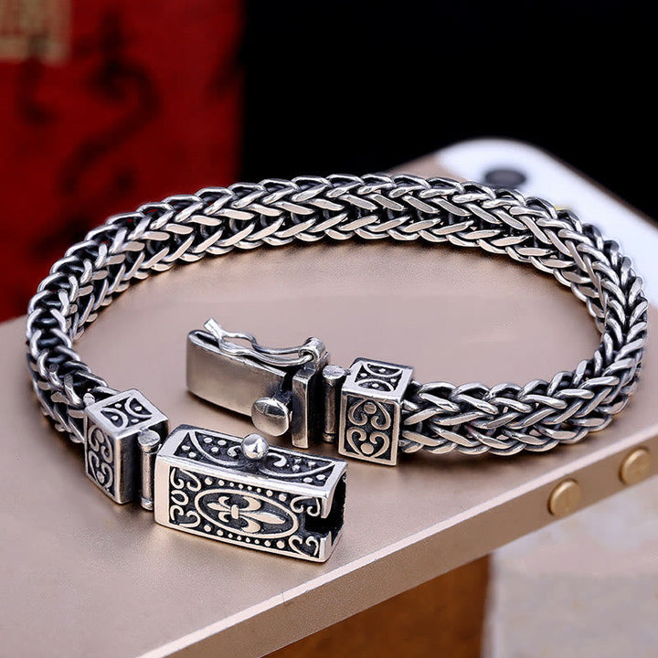 Silbernes Drachen Armband mit Flechtmuster auf beiger Oberfläche.