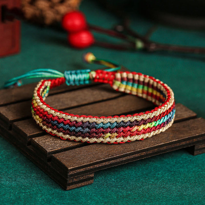 Tibetisches Armband Regenbogen bunt geflochten auf Holzplatte Nahaufnahme