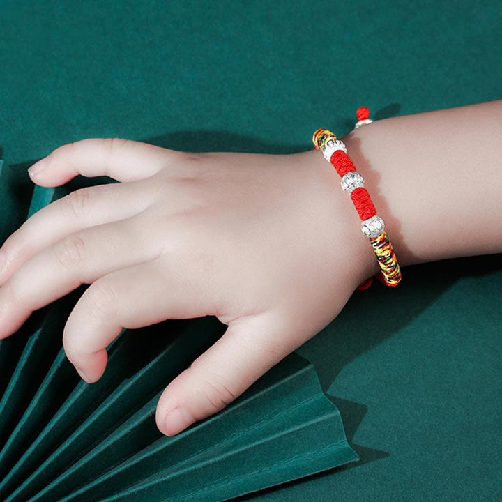 Rotes Armband mit Perlen am Kinderfinger elastisch getragen
