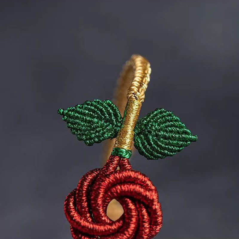 Rotes Seidenarmband mit goldener Perle und grünen Blättern Glück.