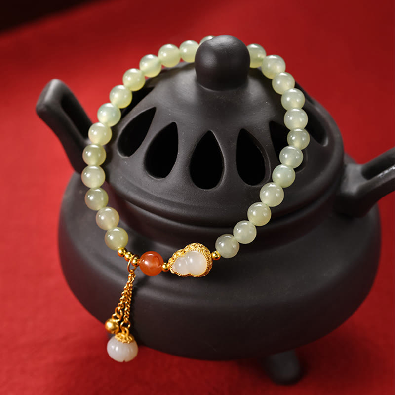Jade Lotus Armband mit goldenen Elementen auf schwarzer Teekanne Dekoration.