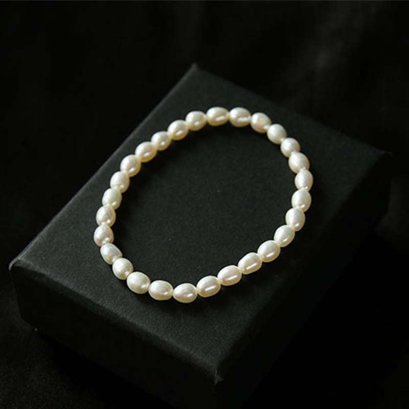 Armband Perle – Heilung: Elegantes Perlarmband mit cremefarbenen Perlen auf schwarzem Displaykissen.