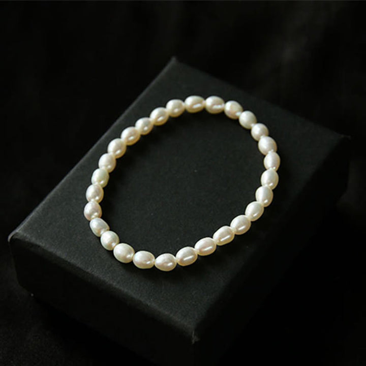 Armband Perle – Heilung: Elegantes Perlarmband mit cremefarbenen Perlen auf schwarzem Displaykissen.