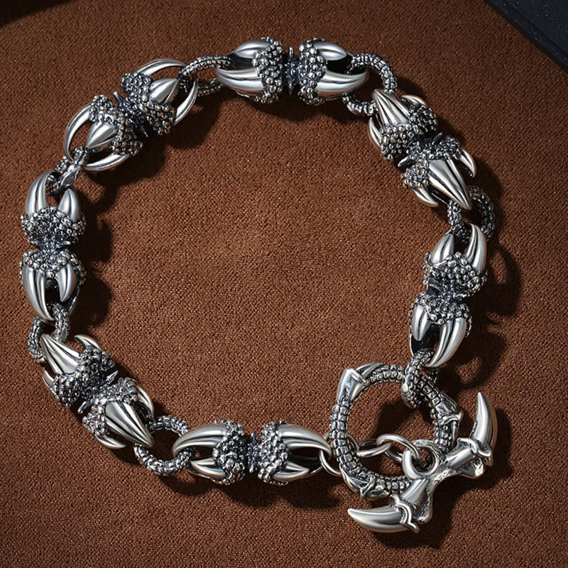 Silbernes Drachen-Armband mitDetailreichen Ornamenten auf braunem Stoff.