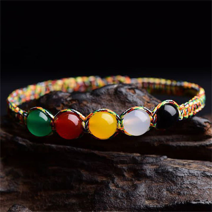 Armband Achat Fünf Elemente mit bunten Steinen auf dunklem Holz.