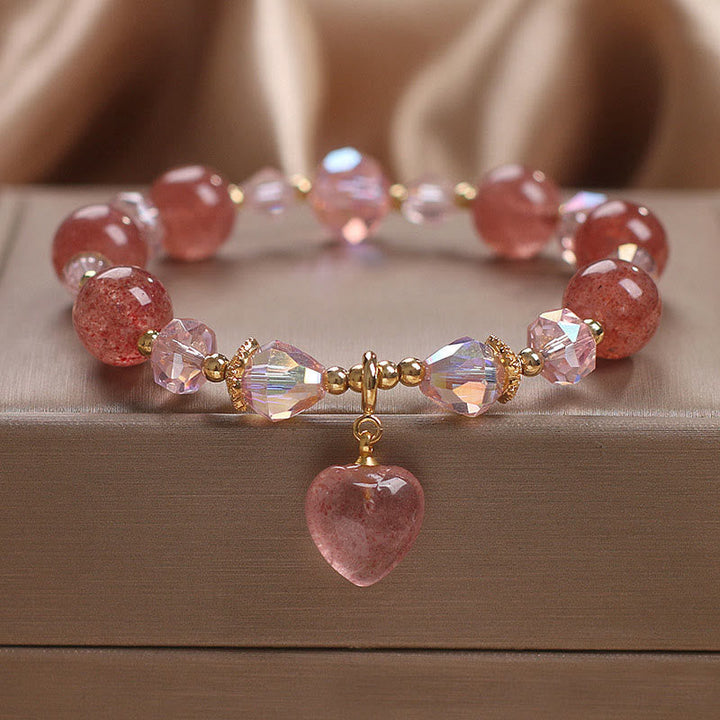Armband Erdbeerquarz Kristall rosé Perlen Herzanhänger Flachliege elegante Schmuckaufnahme