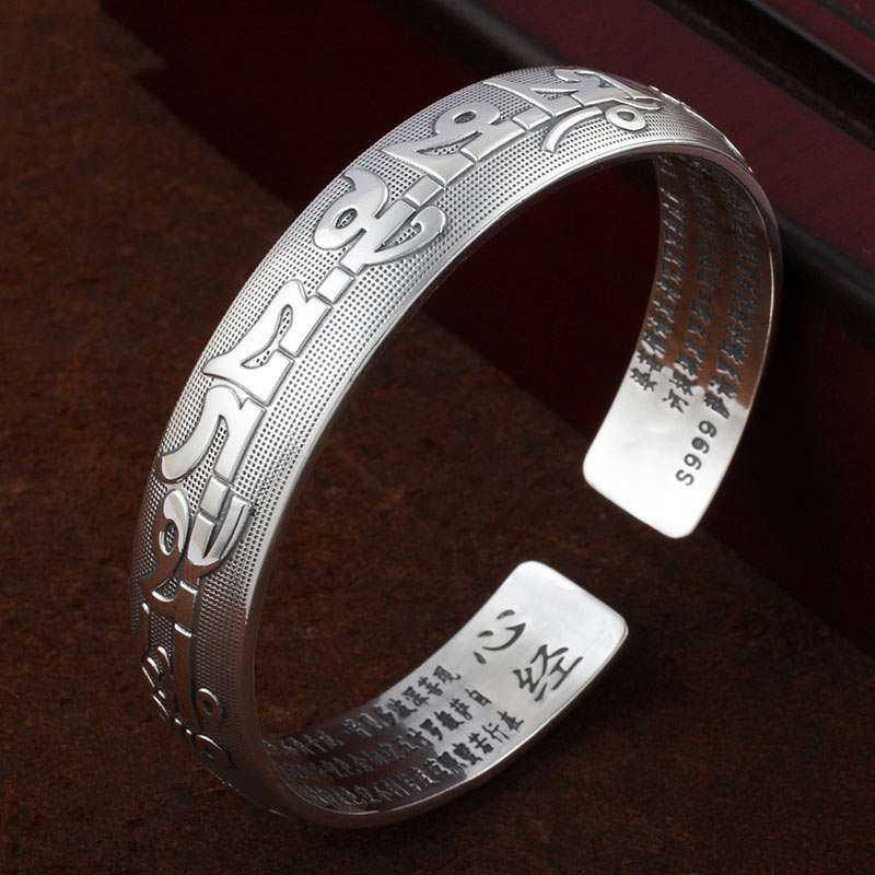 Tibetisches Silber Armband mit Sanskrit Gravur auf braunem Hintergrund.