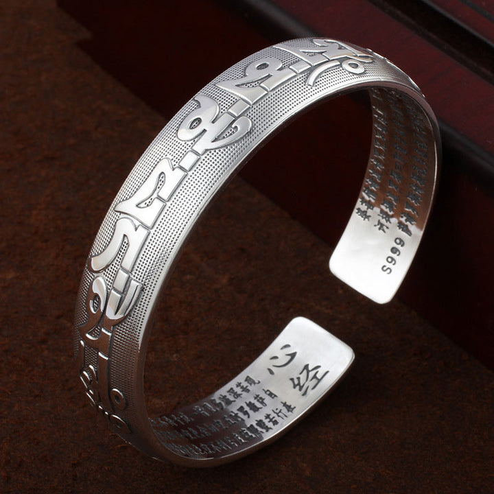 Tibetisches Silber Armband mit Sanskrit Gravur auf braunem Hintergrund.