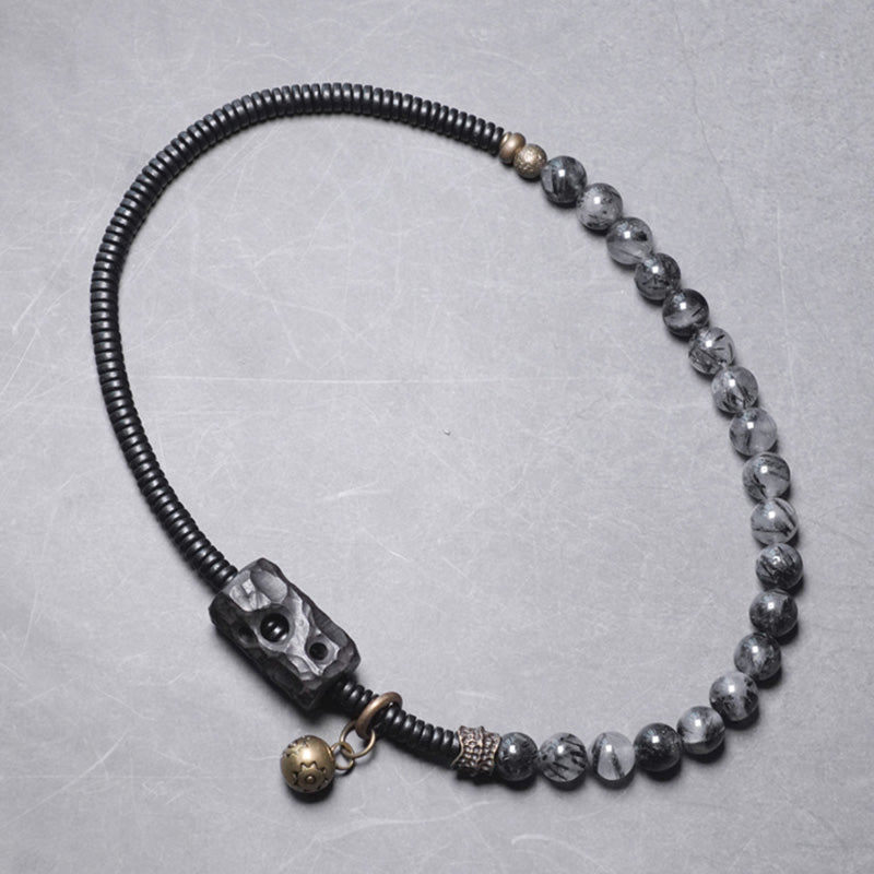 Armband mit schwarzen Perlen und metallischen Akzenten auf grauem Hintergrund.