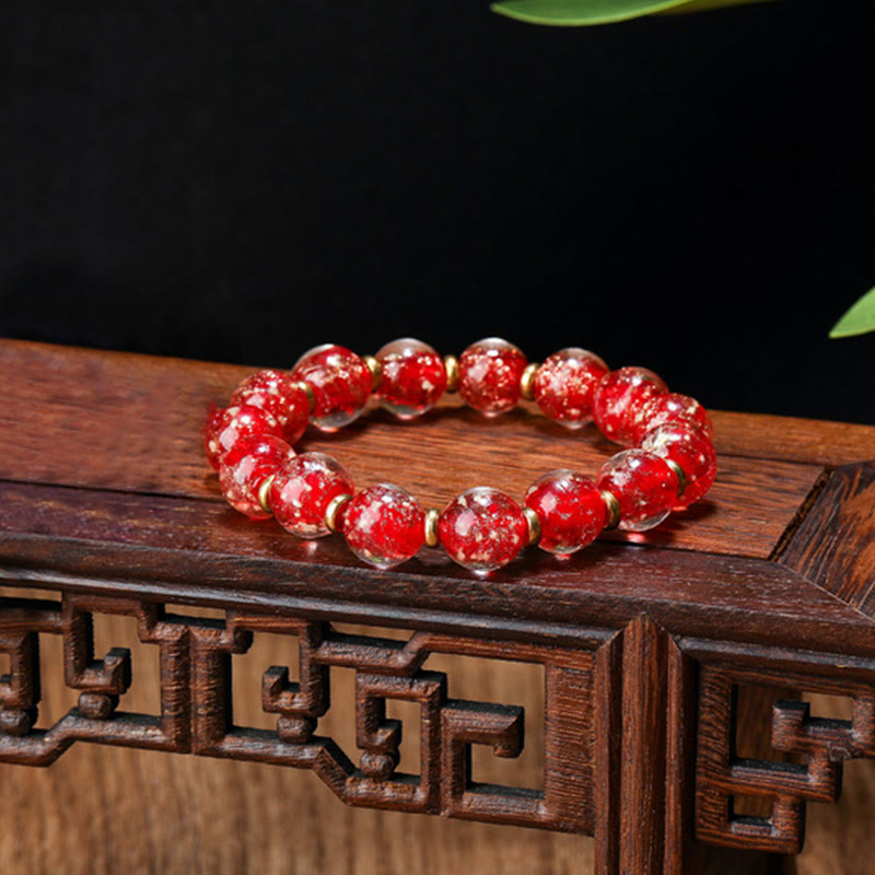 Rotes Kristallarmband mit goldenen Perlen auf Holzoberfläche elegant.